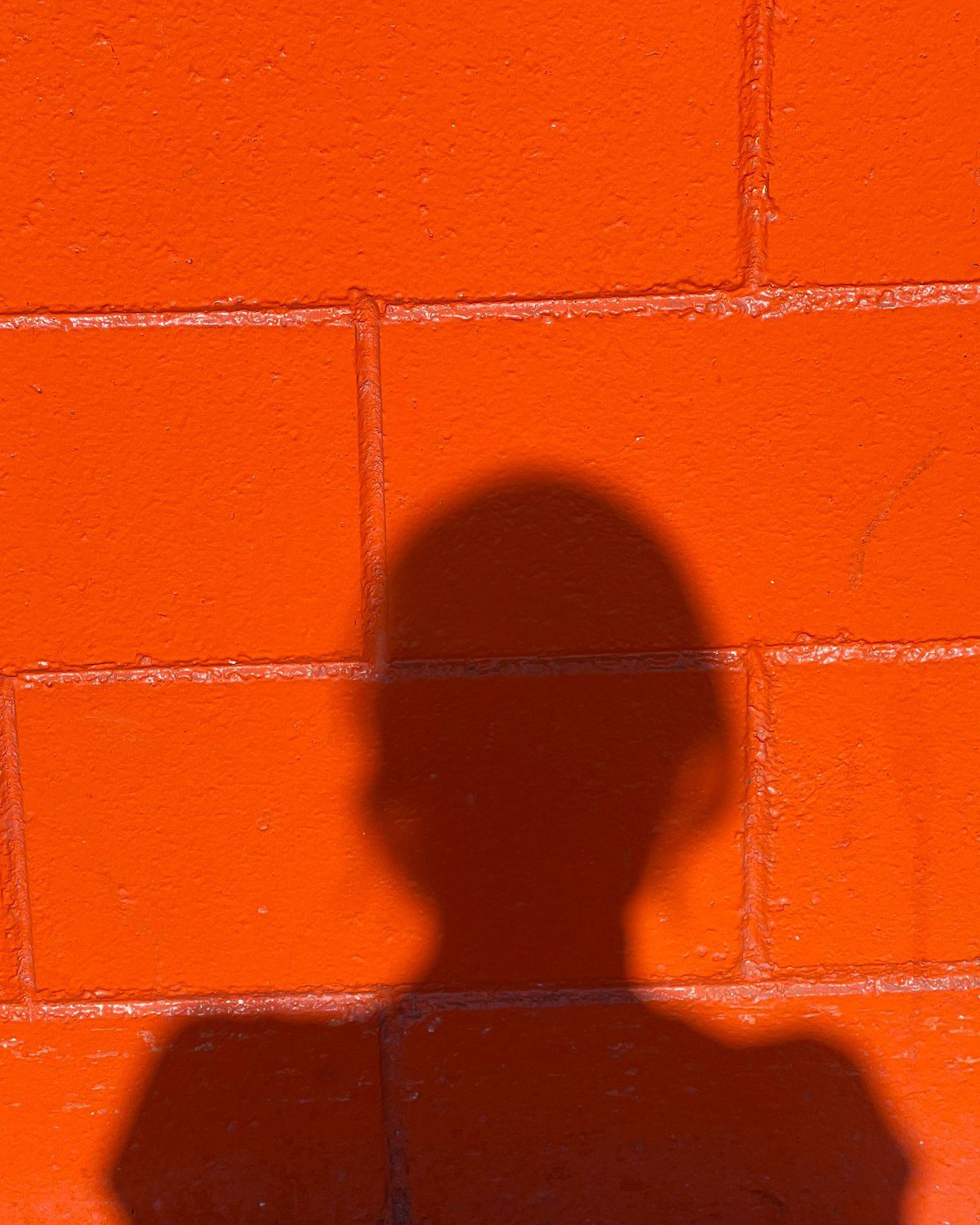 Schaduw van een figuur op een oranje bakstenen muur.